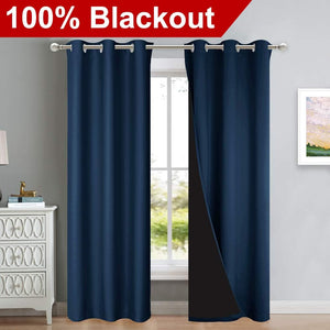 Navy blue blackout curtains with silver grommet tops on a rod. One panel reveals black light-blocking lining.