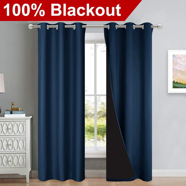 Navy blue blackout curtains with silver grommet tops on a rod. One panel reveals black light-blocking lining.