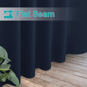 Close-up of navy blue curtains with smooth fabric and prominent flat seam detail, touching a wooden floor.