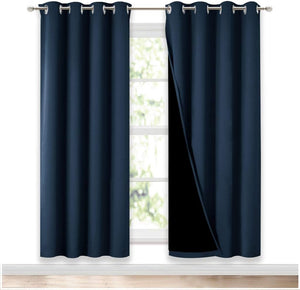Navy blue blackout curtains with silver grommet tops, one panel pulled back to show black lining.
