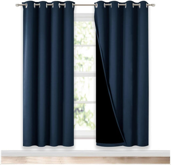 Navy blue blackout curtains with silver grommet tops, one panel pulled back to show black lining.