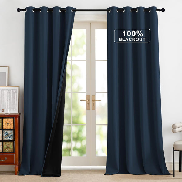 Navy blue blackout curtains with metal grommet top, one pulled back revealing black lining.