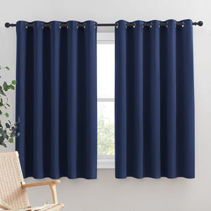 Navy blue blackout curtains with metal grommets hanging on a black window rod.