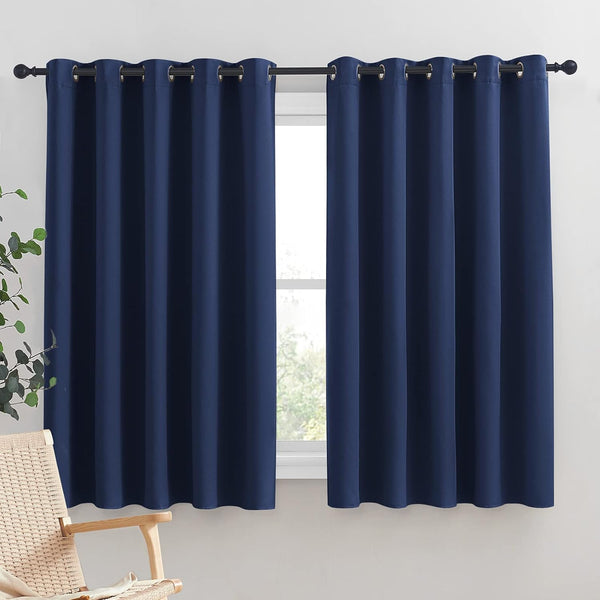 Navy blue blackout curtains with metal grommets hanging on a black window rod.