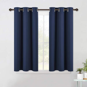 Pair of navy blue blackout curtains with silver grommet top on a dark bronze rod over a window.