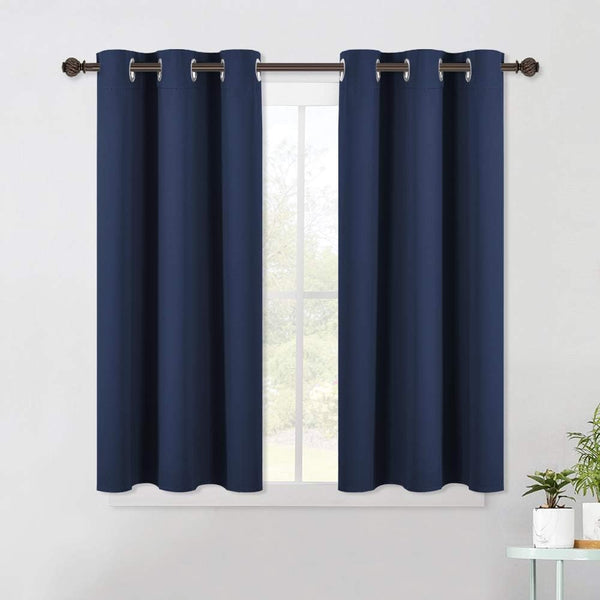 Pair of navy blue blackout curtains with silver grommet top on a dark bronze rod over a window.