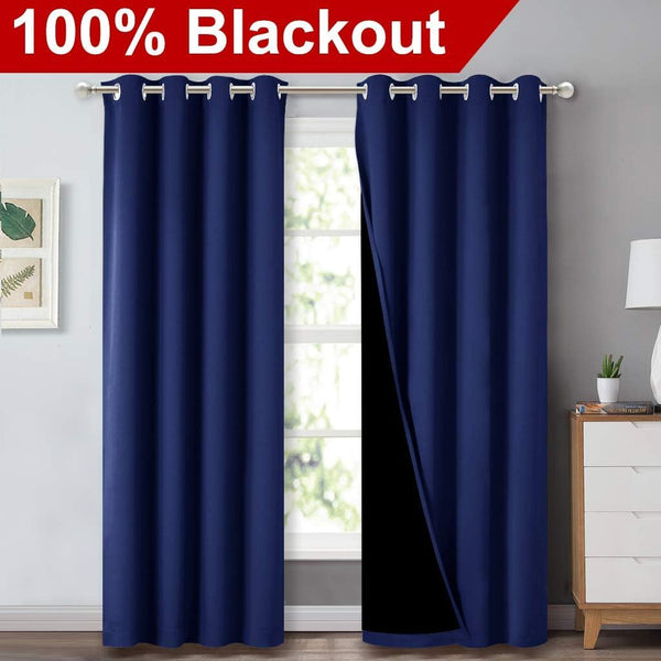 Deep navy blue grommet top blackout curtains hanging over a window, revealing a black lining.