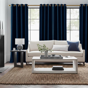 Two panels of rich navy blue curtains with bronze grommets hanging on a gold rod in a modern living room.
