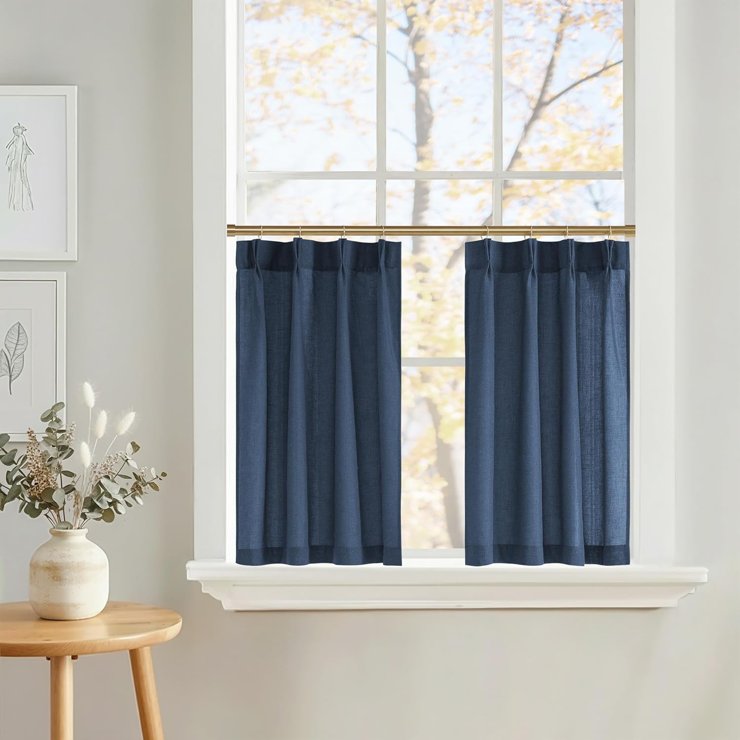 Deep navy blue linen-blend cafe curtains with pleated tops on a brass rod, providing privacy to a window.