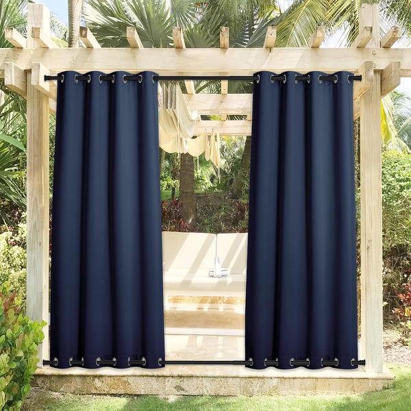Navy blue outdoor grommet curtains hanging from a wooden pergola rod in a garden.