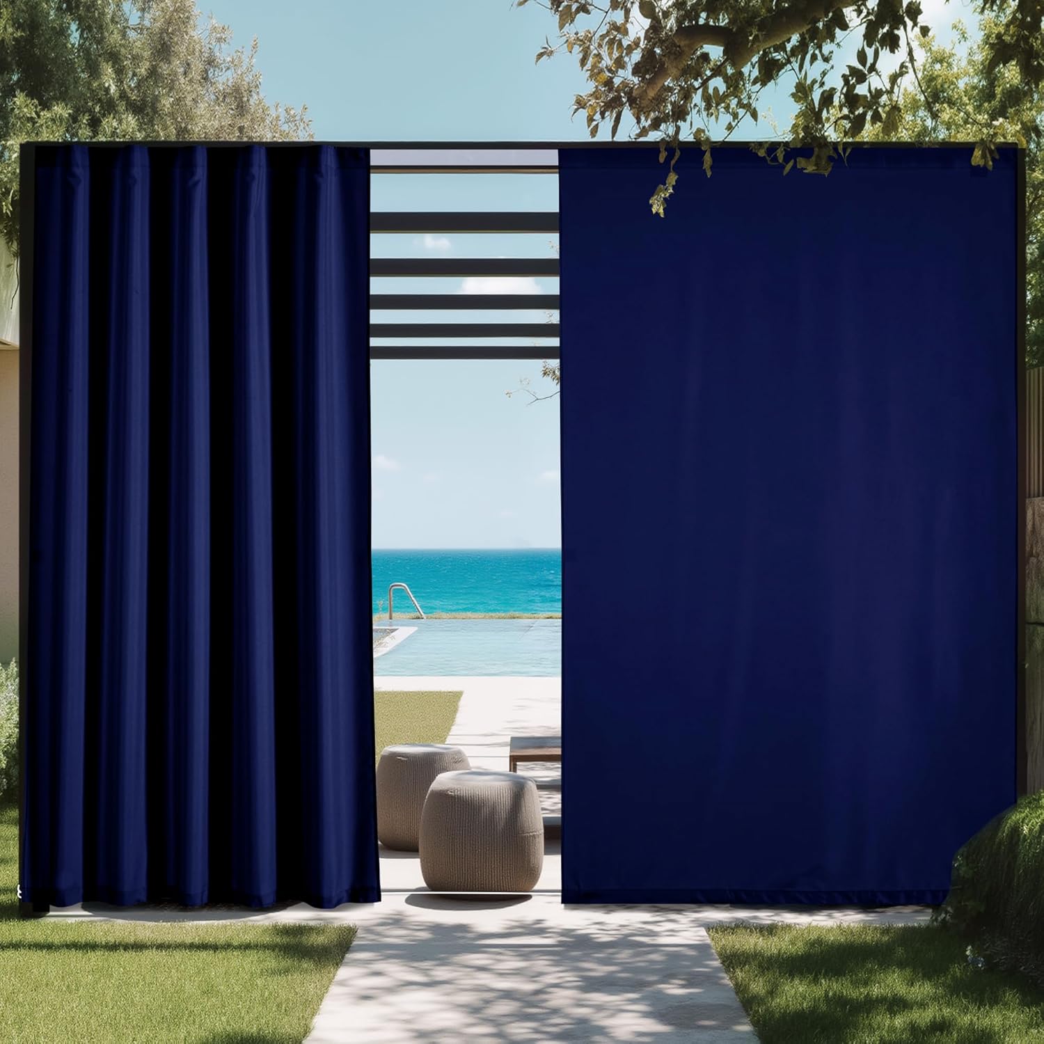 Navy blue weather-resistant outdoor privacy drapes by a modern poolside with ocean background.