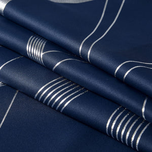 Close-up of navy blue fabric with shimmering silver metallic foil pattern featuring abstract curves and parallel lines.