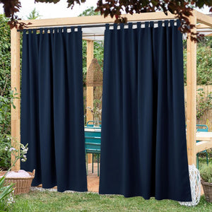 Two panels of navy blue tab top outdoor curtains on a wooden pergola, creating a private patio area.