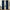 Pair of navy blue velvet pinch pleat curtains hanging on a black rod, pooling on the floor.
