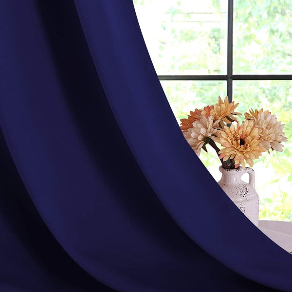 Smooth navy blue curtain panel with elegant folds, partially open by a window displaying flowers.