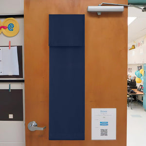 Navy blue fabric door window privacy cover hanging on a light brown classroom door. Features a stitched top flap.
