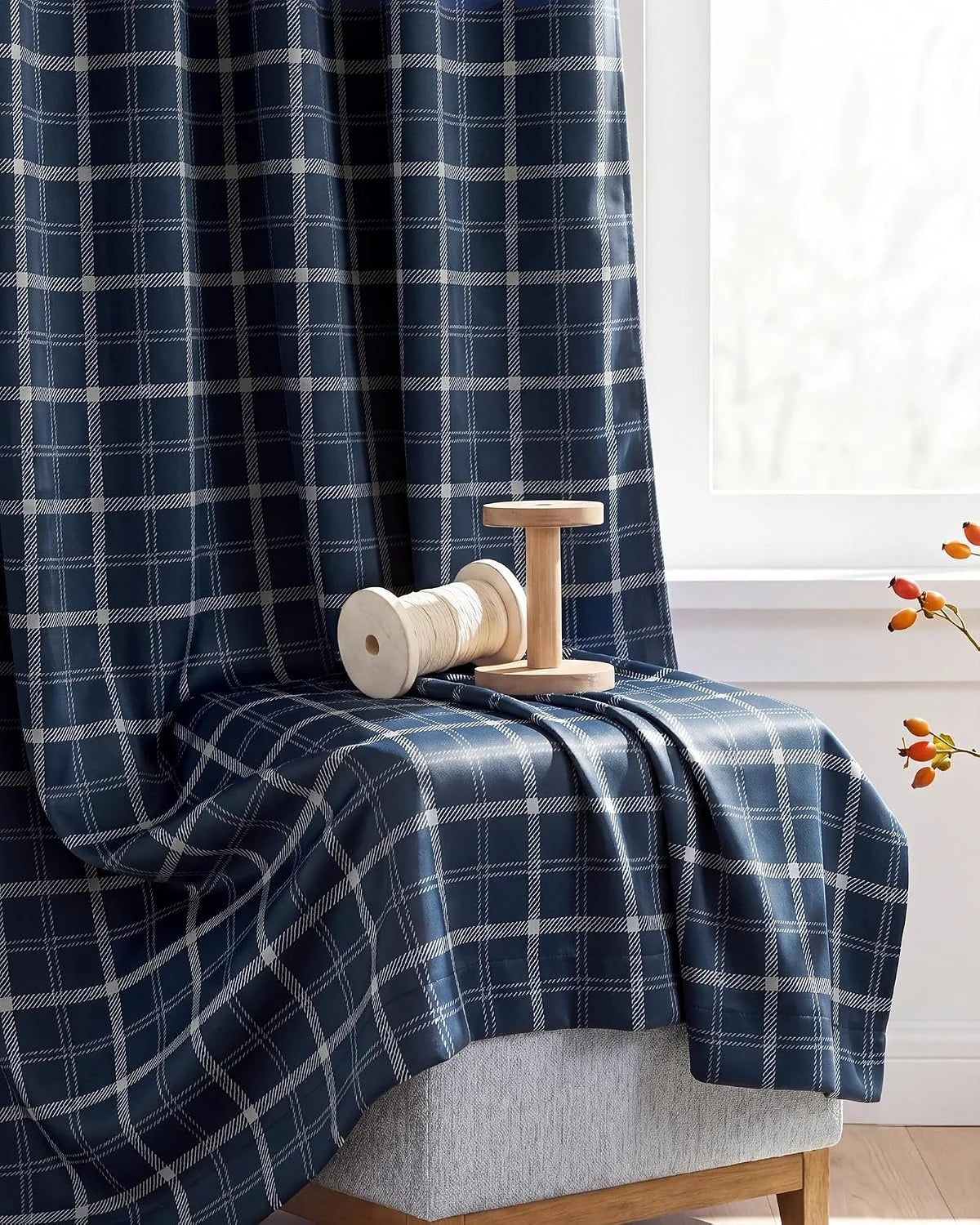 Navy plaid fabric draped over a chair by a window with wooden spool accents