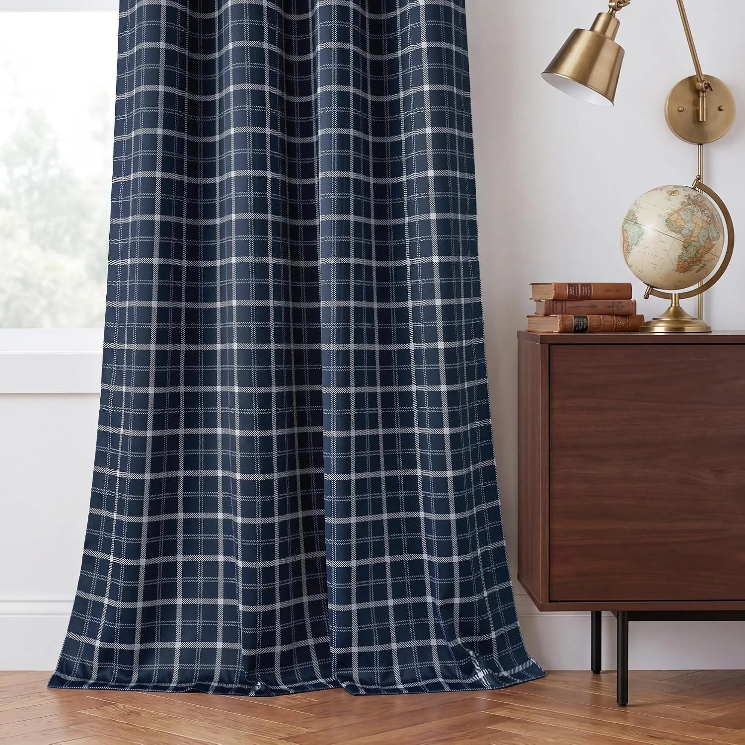 Navy blue plaid curtain panel beside a walnut cabinet with brass lamp and globe