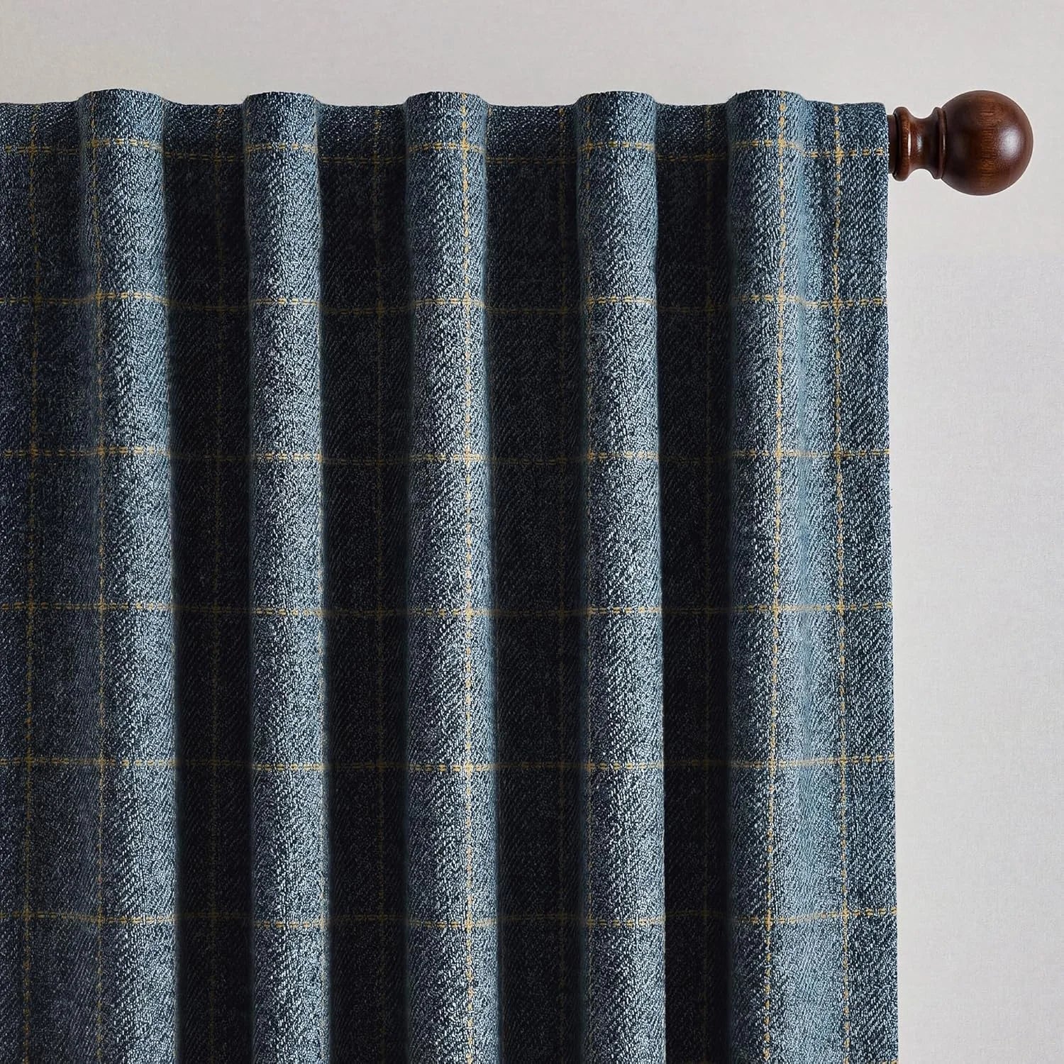 Navy blue and yellow plaid curtain made of heavy textured fabric, hanging on a dark wood rod.