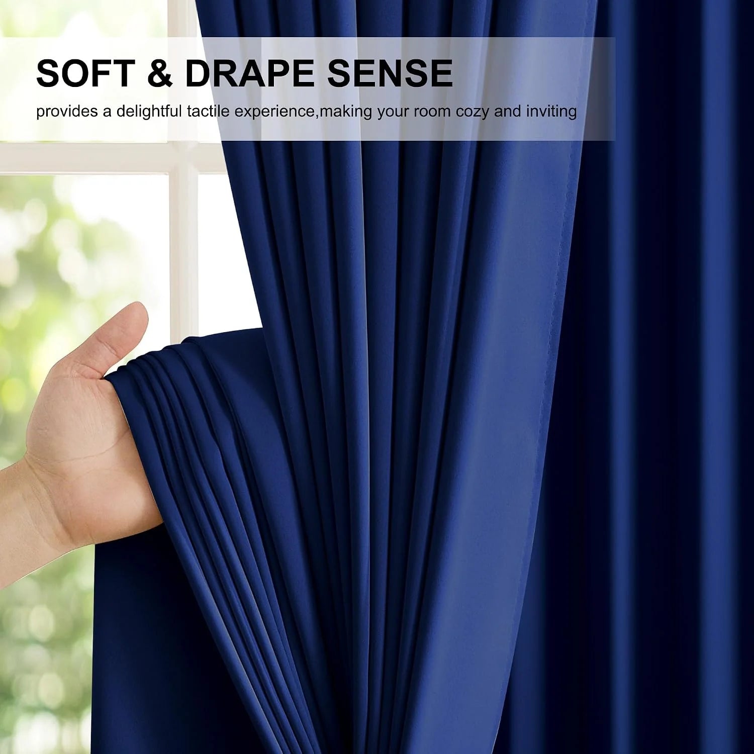 Hand holding navy blue curtain fabric by a bright window, showing soft drape