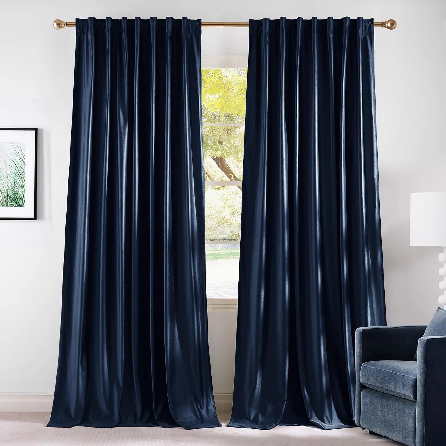 Dark navy velvet curtains hanging on a gold rod in a bright modern room