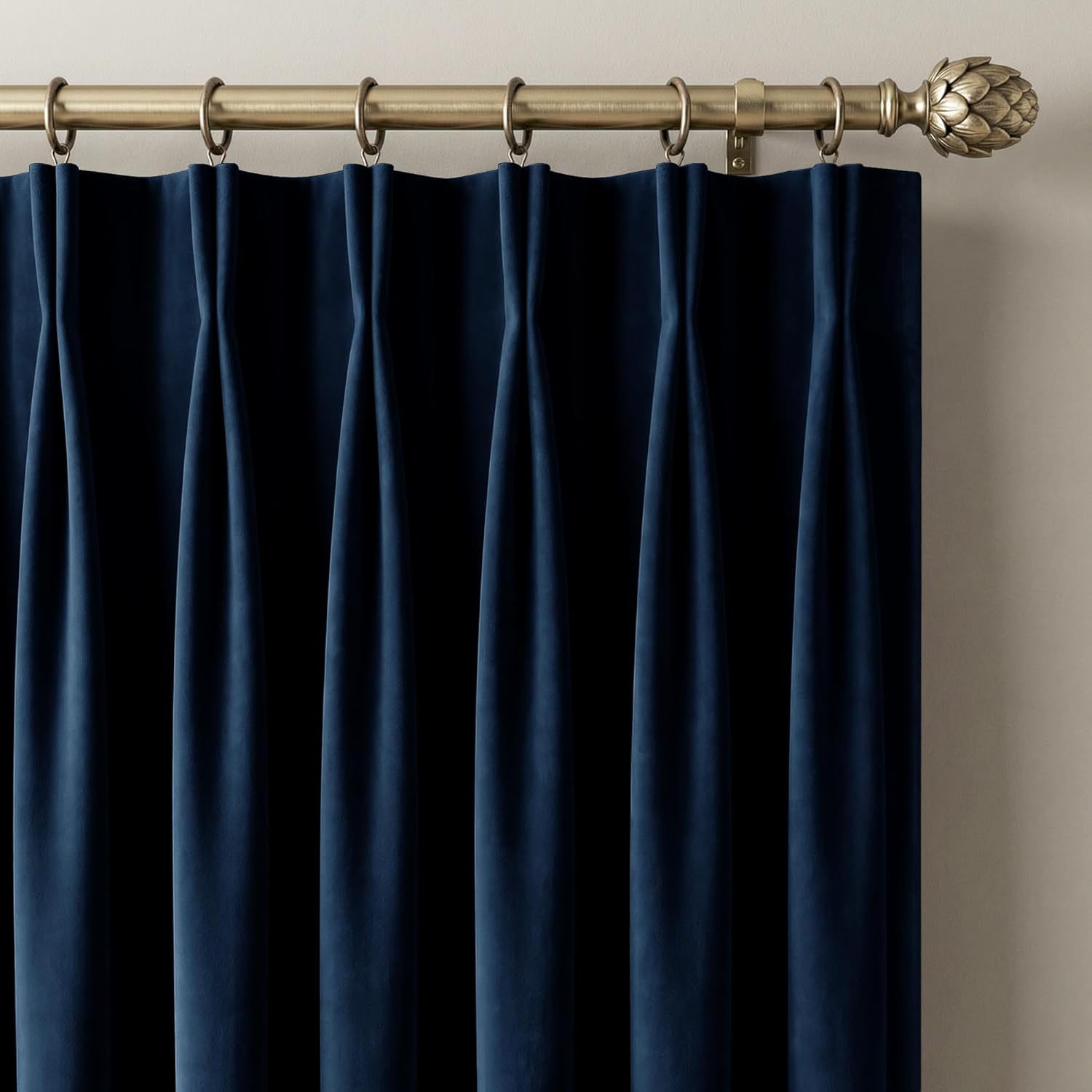 Navy blue velvet pinch pleat curtains on brass rod with rings and artichoke finial.