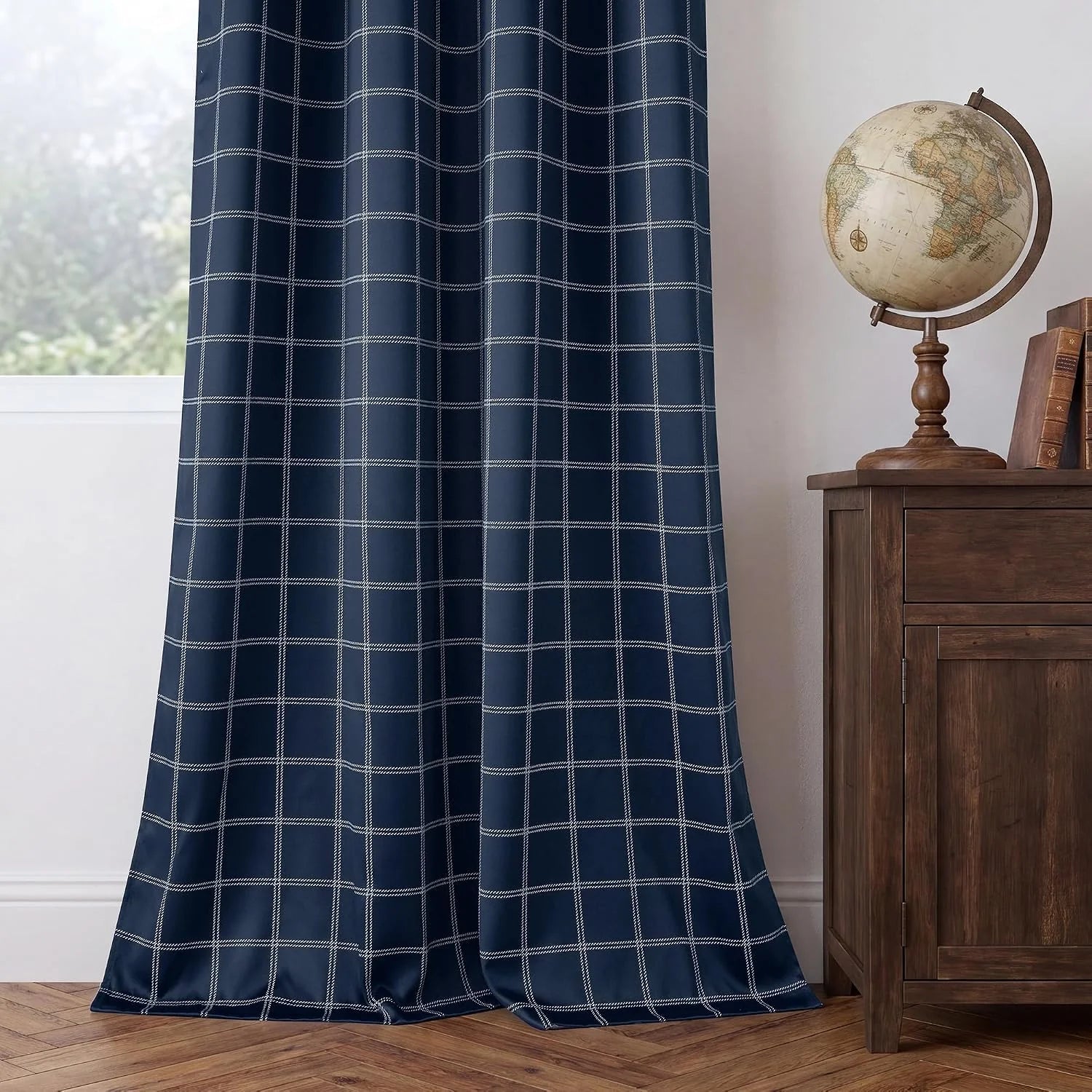 Navy curtain panel with white windowpane plaid beside a wooden cabinet and globe