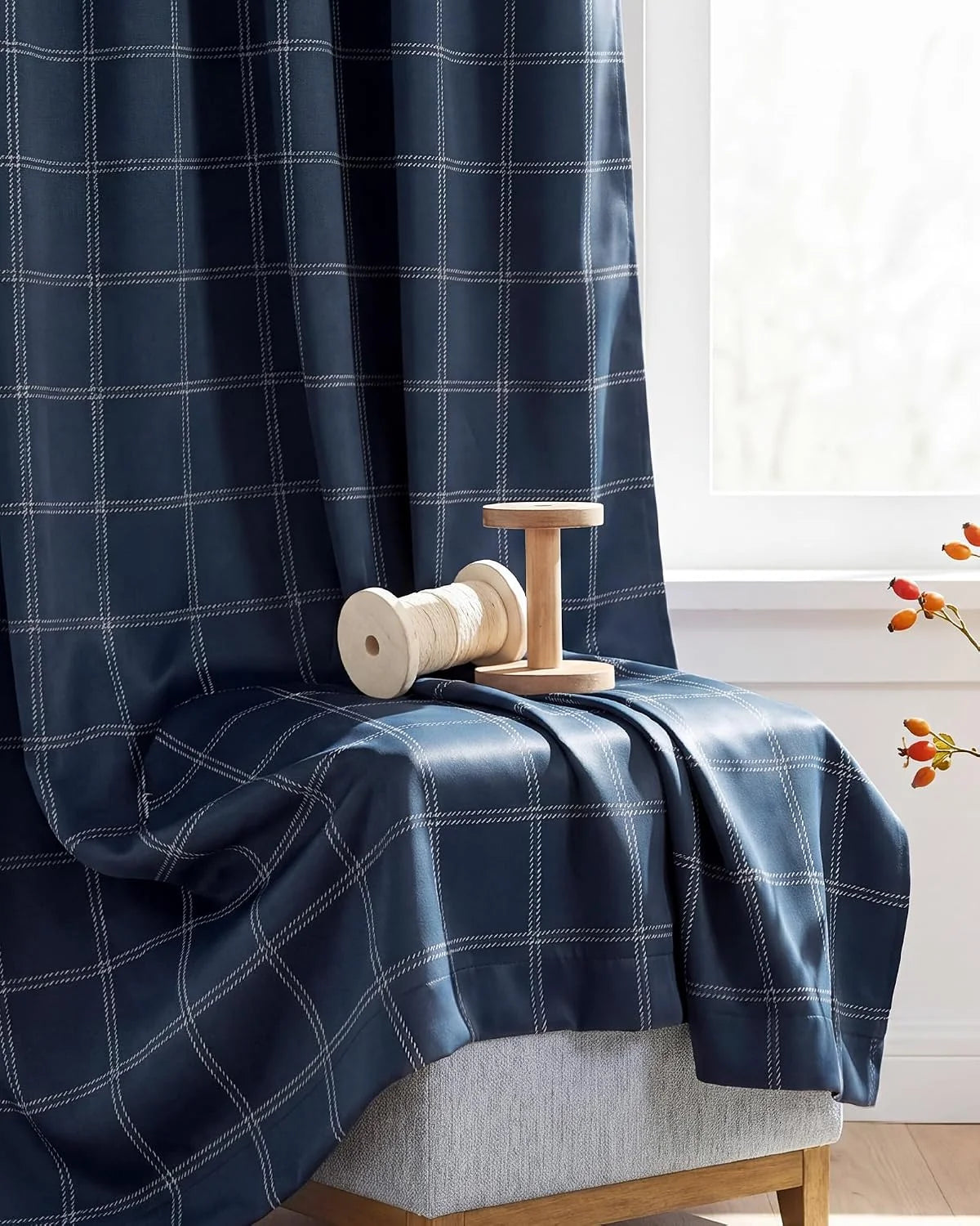 Navy windowpane curtain panel draped on a bench beside a bright window