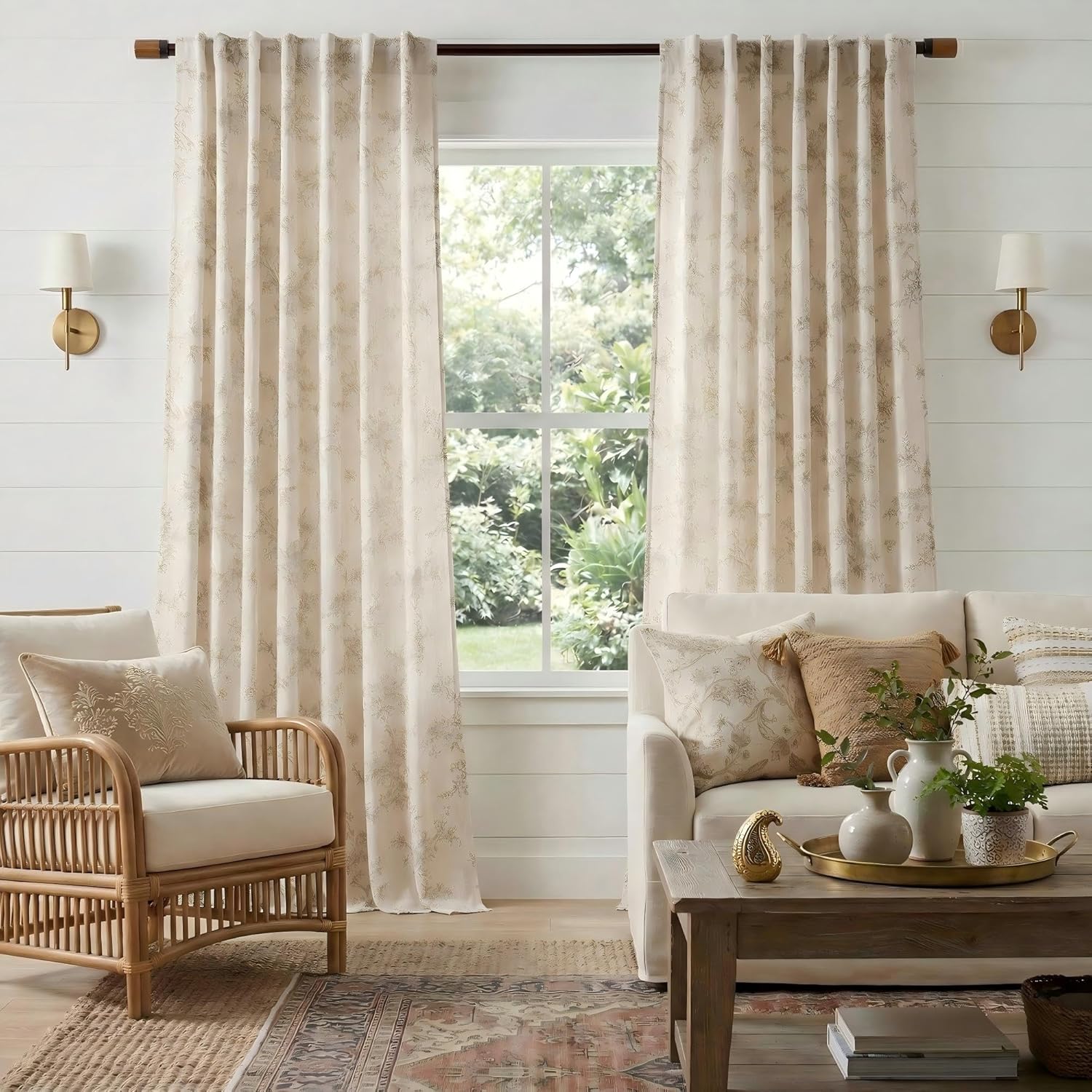 Light beige curtains featuring a subtle gold botanical pattern, hung with pleats on a wooden rod in a bright living room.