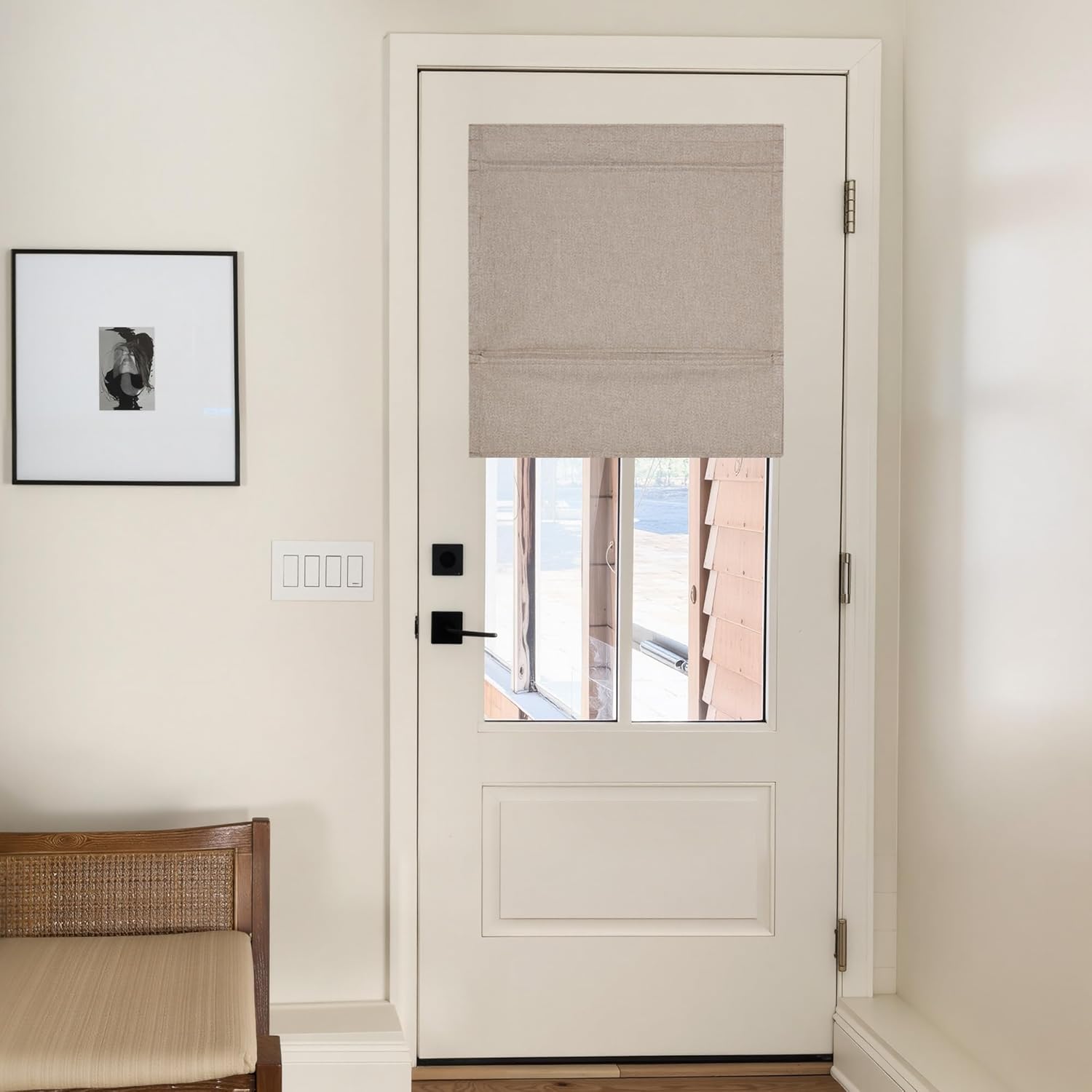 Light beige linen Roman shade with visible folds covering the top window of a white door in a contemporary room.