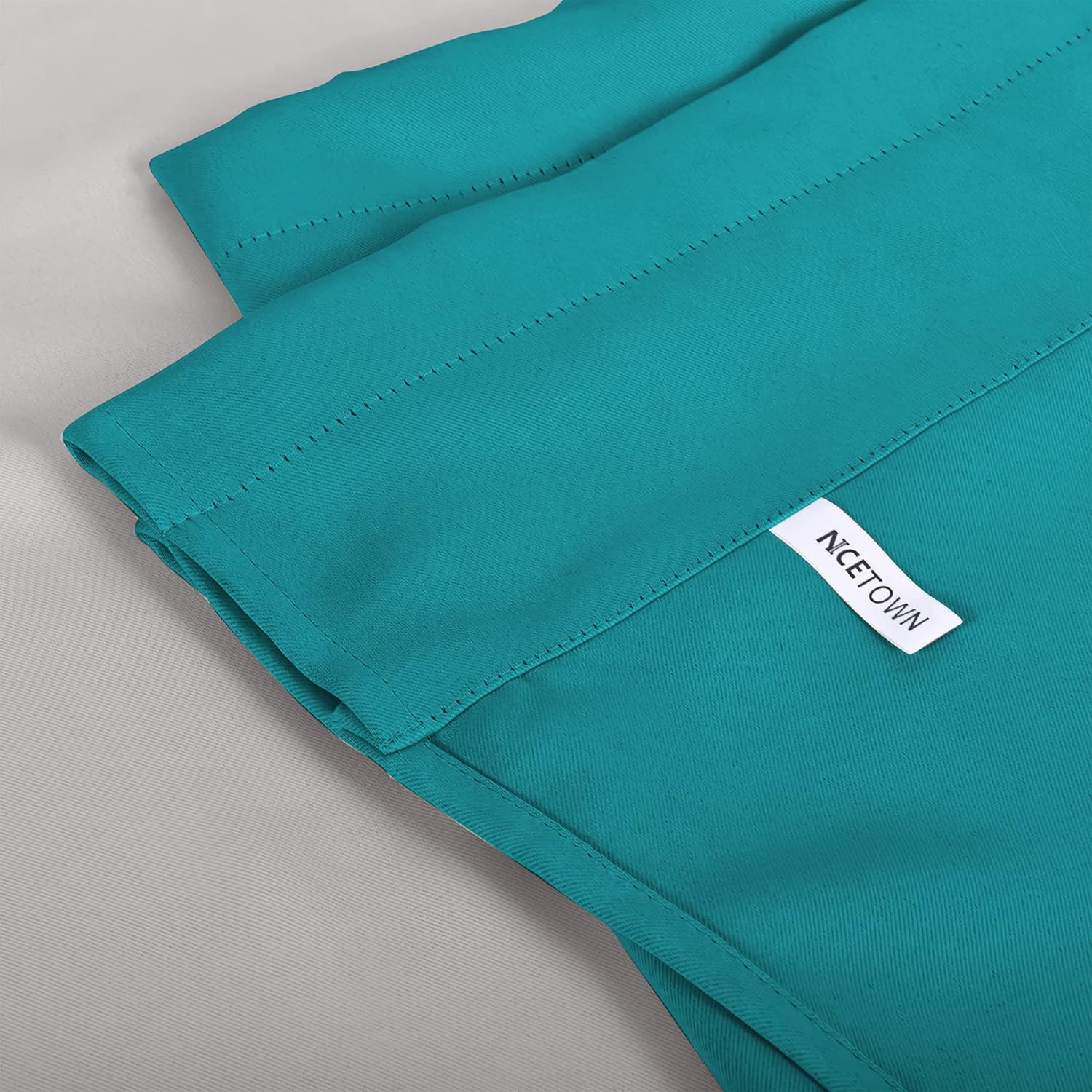 Teal NICETOWN curtain panel detail, showing the fabric texture, top stitching for a rod pocket, and white brand label.