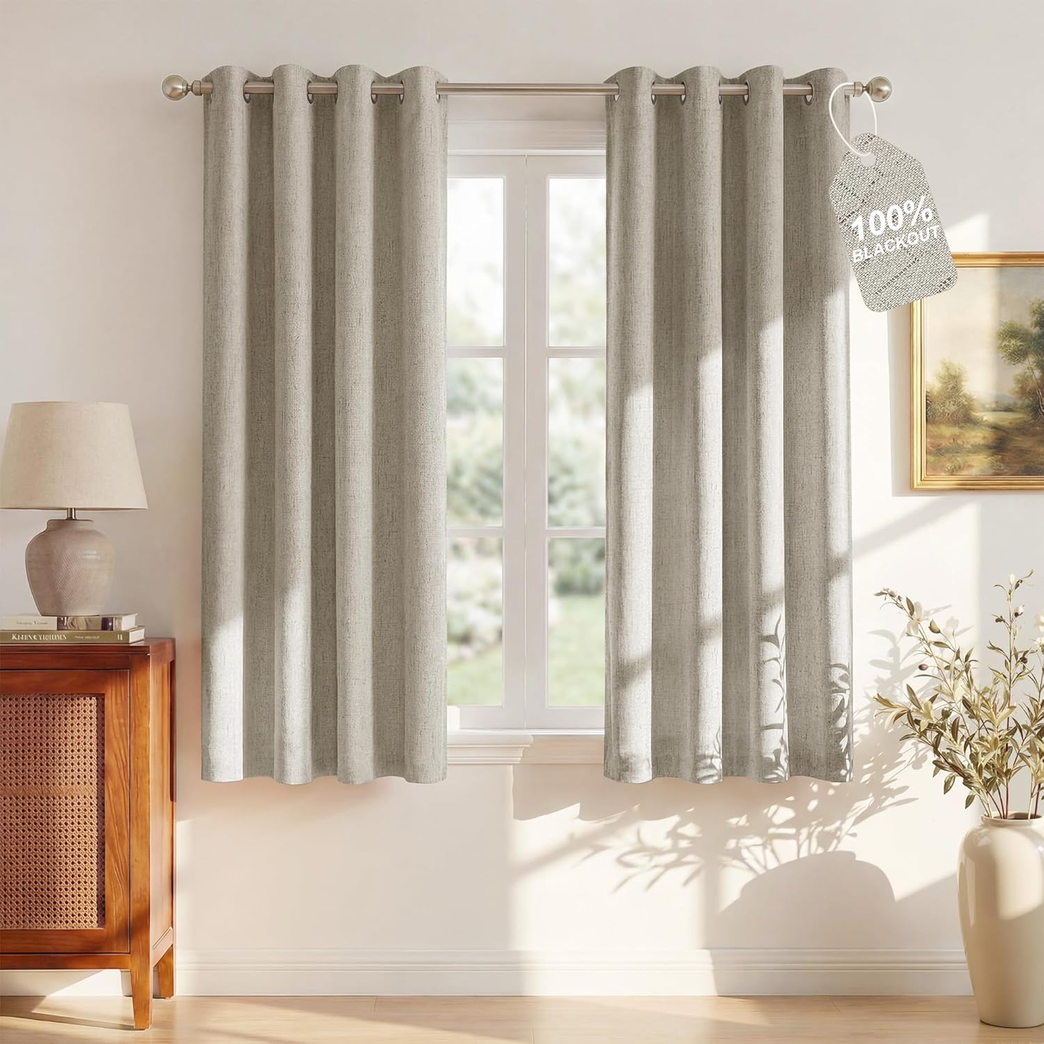 Oatmeal heathered blackout curtains with brushed nickel grommet tops hung on a sunlit window.