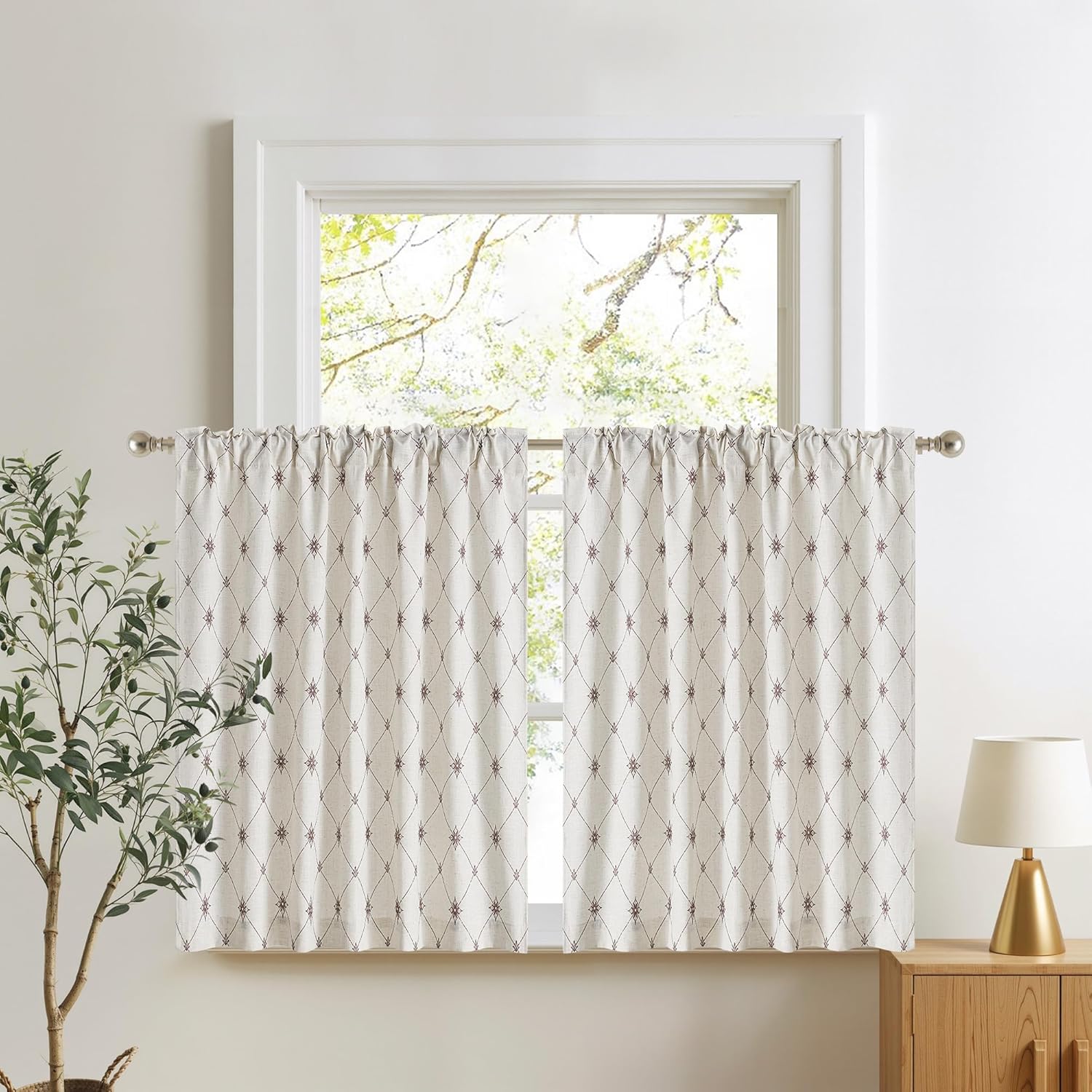 Off-white cafe curtains with a reddish-brown embroidered diamond pattern and rod pocket top, hanging on a window.