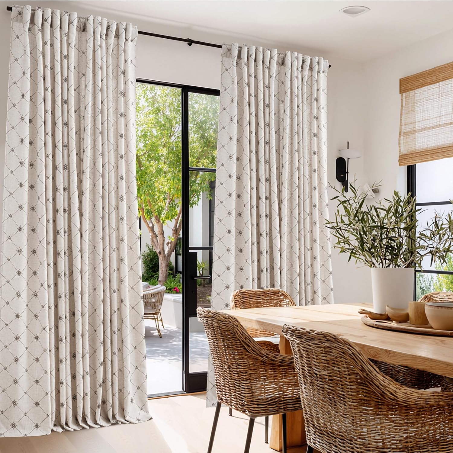 Off-white linen-look curtains with subtle dark geometric pattern and pinch pleats in a bright dining room.