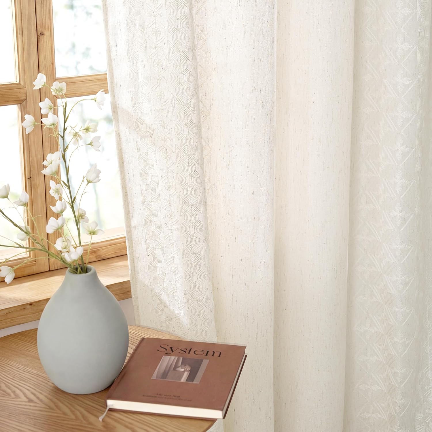 Light filtering off-white semi-sheer curtains with subtle geometric pattern next to a wooden window.