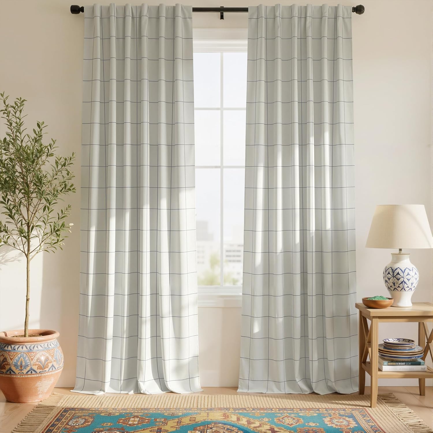 A pair of off-white curtains with a subtle dark grid pattern, softly filtering light in a bright room.