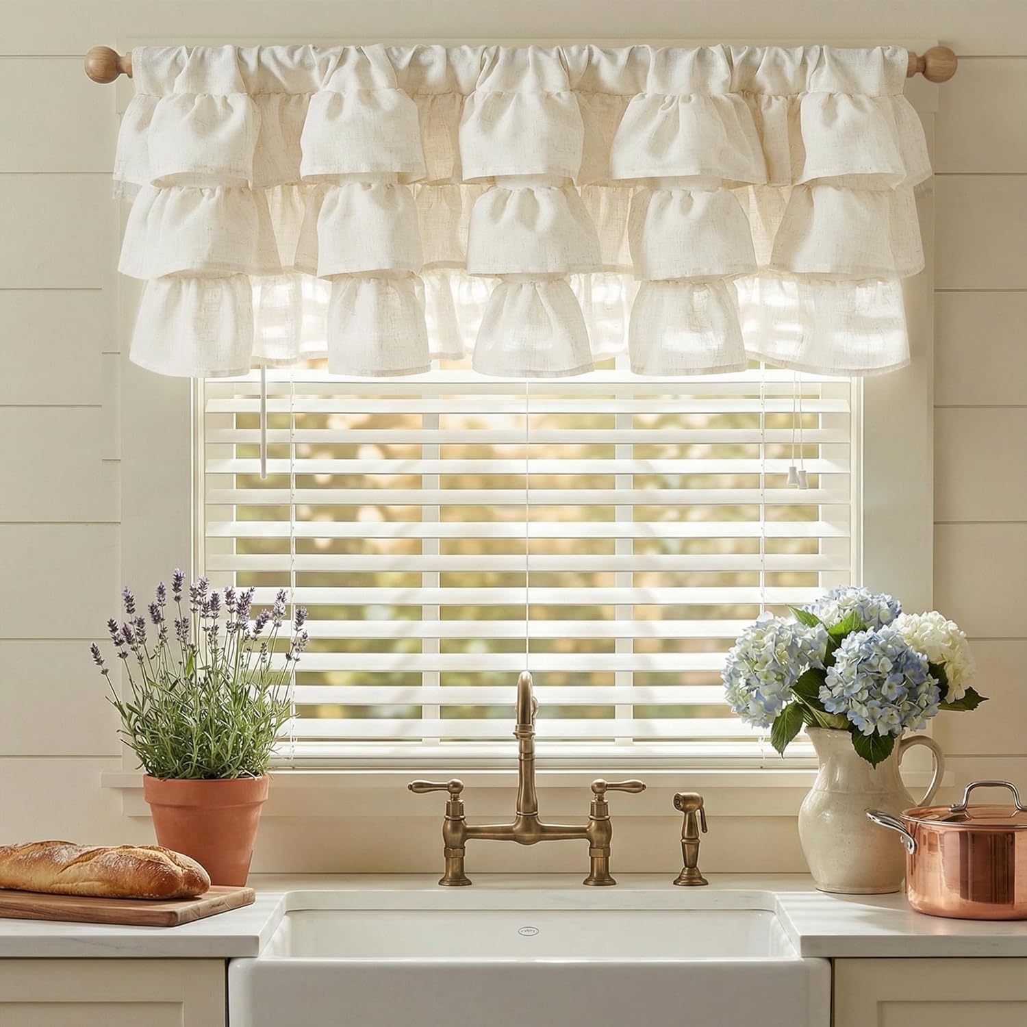 Off-white layered ruffled linen window valance, providing a charming farmhouse look above a kitchen sink.