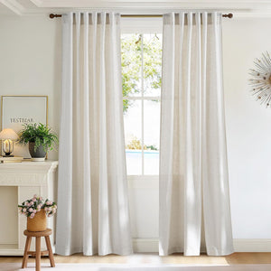 Pair of off-white textured linen back tab curtains hanging from a dark rod, softly filtering light.
