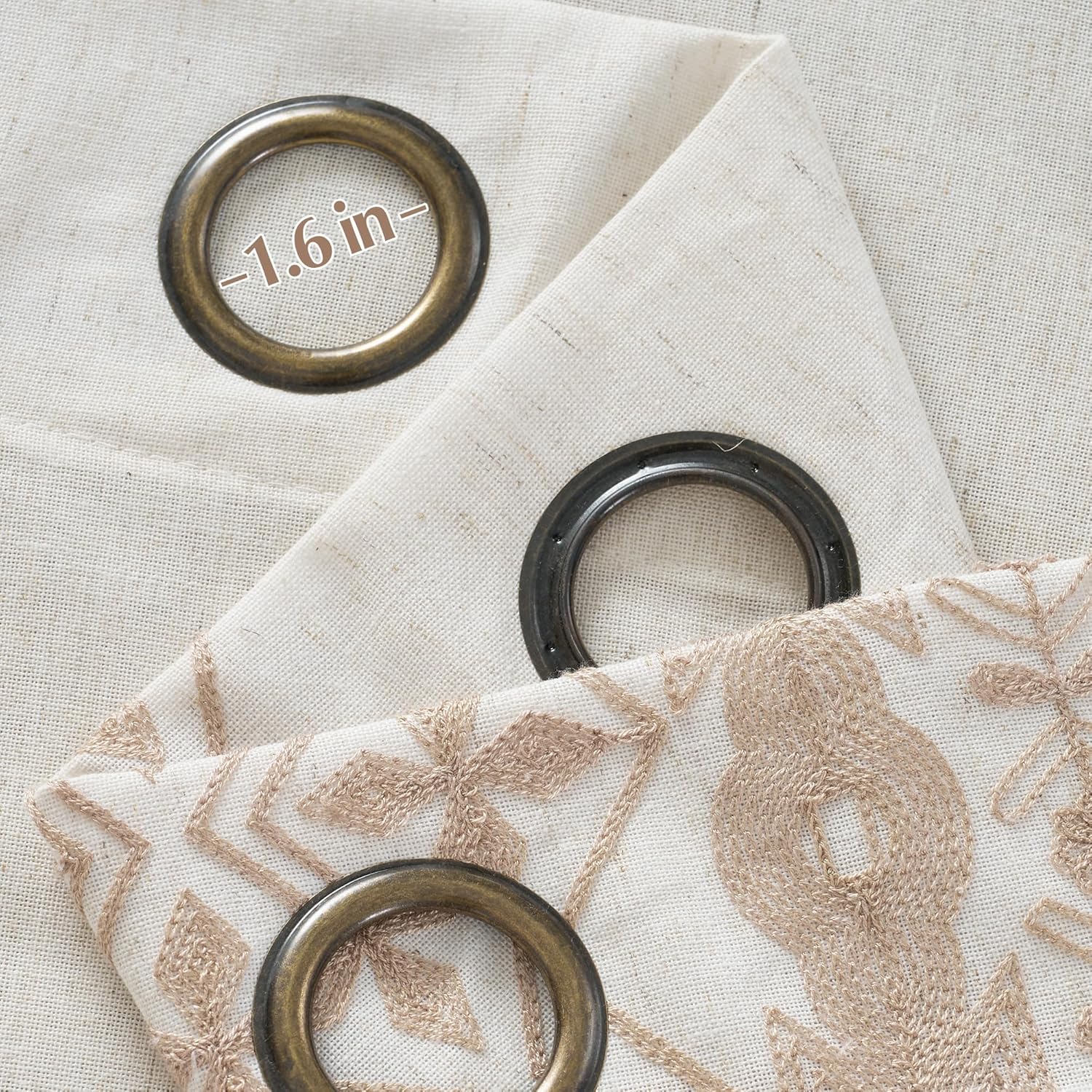 Close-up of off-white linen blend curtain fabric with tan geometric embroidery and a 1.6-inch dark bronze grommet.