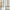 Off-white textured curtain panel with decorative sage green geometric and floral embroidery patterns by a wooden window frame.