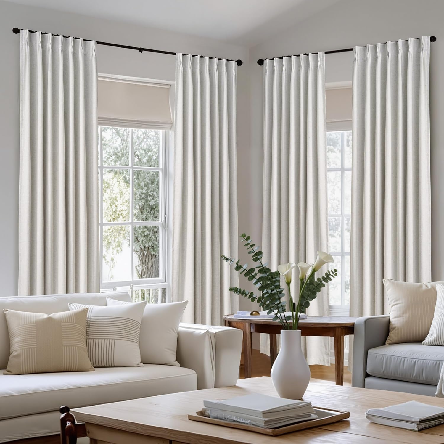 Off-white linen textured pinch pleat curtains on black rods in a bright modern living room.