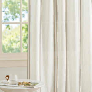 Light filtering off-white curtain with thin and thick vertical taupe stripes, diffusing light from a window.
