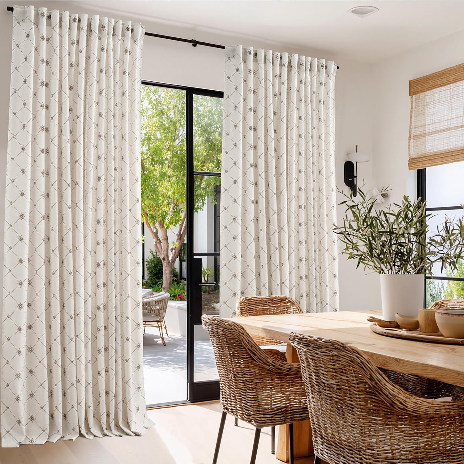 Elegant off-white pinch pleat curtains with a subtle brown diamond and starburst pattern, framing a glass door.