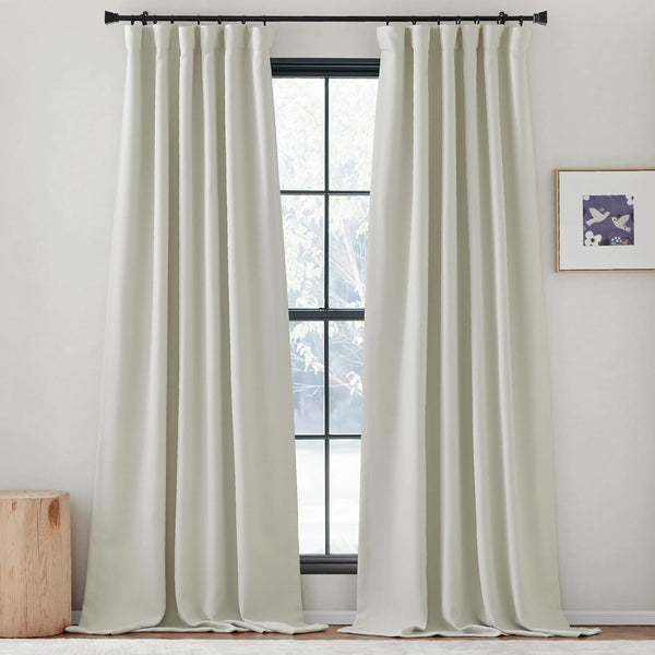 Pair of thick off-white pleated curtains hanging on a black rod over a large window.