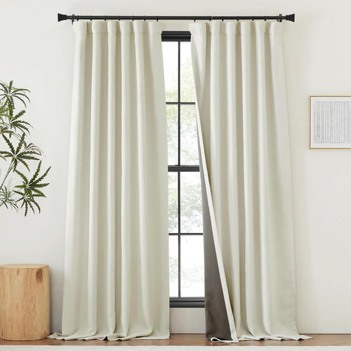 Off-white rod pocket blackout curtains with dark lining, hung on a black rod, one panel partially open.