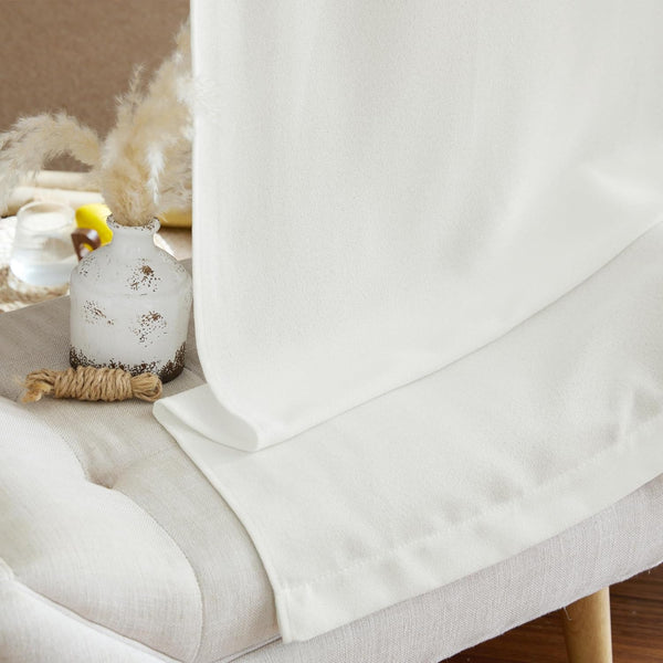 Off-white textured woven curtain panel draped elegantly over a light beige tufted bench.