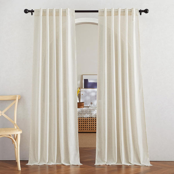 Pair of off-white textured linen blend tab top curtains hanging from a black rod, touching a wooden floor.