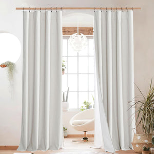 Pair of textured off-white linen curtains hanging with clip rings on a wooden rod in a bright, modern room.