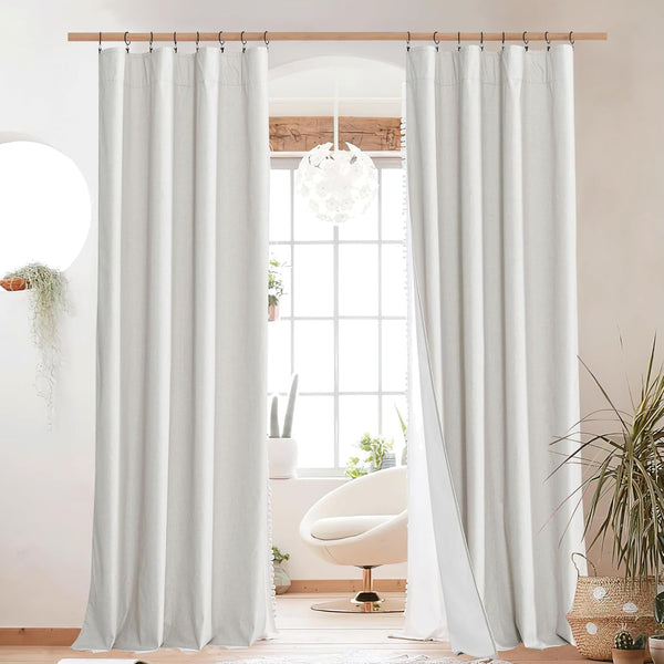 Pair of textured off-white linen curtains hanging with clip rings on a wooden rod in a bright, modern room.