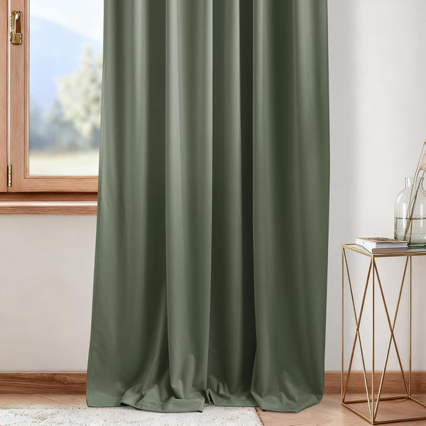 Full length olive green blackout curtain panel with soft folds, hanging by a wooden window.